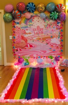 a rainbow themed birthday party with balloons and streamers on the wall, candy land backdrop