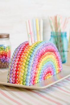 there is a cake made to look like a rainbow with candy sticks sticking out of it