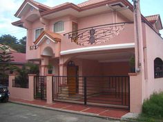 a car parked in front of a pink house with wrought iron railings on the balcony