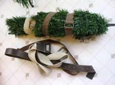 two christmas tree branches are wrapped in brown and white ribbon, one has a cell phone attached to it