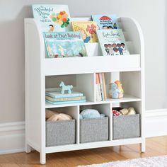 a white book shelf filled with books on top of a hard wood floor