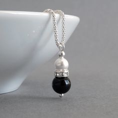 Simple and elegant in design, this black onyx and white pearl necklace would be ideal for bridesmaids in a monochrome themed wedding. A lone, white glass pearl sits in a crystallised band above a jet black onyx bead. This glass pearl and crystal teardrop hangs from a Sterling silver corb chain.  The 18 inch corb chain is a more ornate alternative to the standard snake chain. The way the chain is cut and assembled means it really glimmers in the light. The pearl drop pendant measures 2.3cm high a Elegant Black Bridal Necklace For Formal Occasions, Elegant Dangle Necklaces For Bridesmaid Gift, Elegant Black Drop Necklace Gift, Black Pearl Necklace For Wedding, Elegant Black Pearl Necklace For Weddings, Elegant Black Drop Dangle Necklace, Black Pearl Drop Jewelry For Anniversary, Elegant Black Dangle Drop Necklace, Black Pearl Drop Necklace For Gift