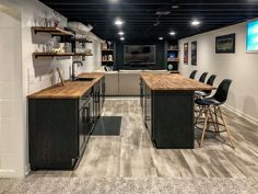 a large open concept kitchen with bar stools and wooden counter tops in an office setting