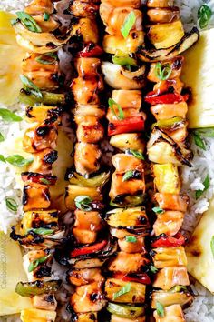 chicken skewers with pineapples and onions on top of rice