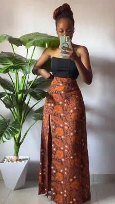 a woman taking a selfie in front of a potted plant wearing an orange skirt