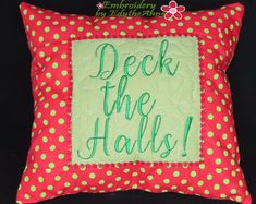 a red and green pillow with the words deck the hall on it's side