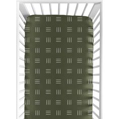 a green sheet with white lines on it in the corner of a crib bed