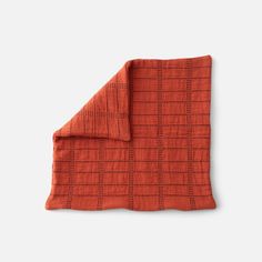 an orange and black checkered blanket folded on top of a white surface with the end of