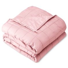 a pink comforter is folded on top of a bed with two pillows and one blanket