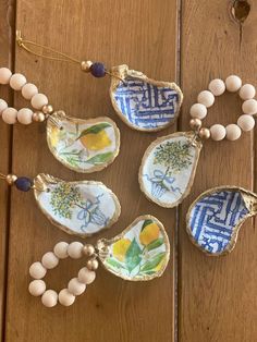 four ceramic ornaments are hanging on a wooden table with beads and bead necklaces