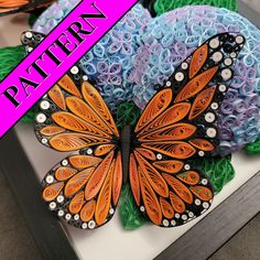 an orange and black butterfly sitting on top of some blue flowers with the words pattern over it