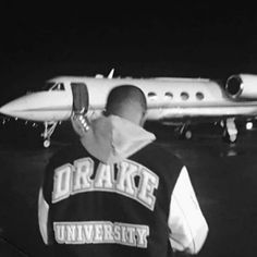 a man standing in front of an airplane on the runway at night with his back turned to the camera