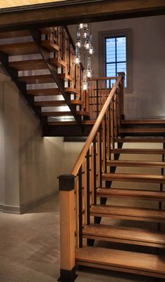 a wooden stair case with chandeliers hanging from it