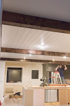 a man standing on a ladder in a room under construction