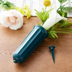 a blue vase with flowers in it sitting on a table next to a pair of scissors