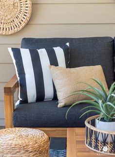 a black and white couch with some pillows on it next to a plant in a basket