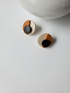 two small wooden buttons sitting on top of a white table next to a bowl and spoon