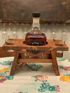 a bottle of whiskey sitting on top of a wooden tray next to two shot glasses