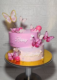 a pink birthday cake with butterflies on top