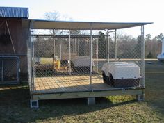 a dog kennel with two dogs in it and one behind the fenced off area