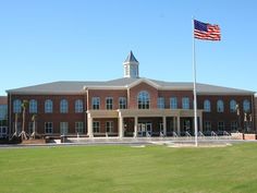 an american flag flying in front of a large brick building with a clock tower on top