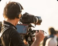 a man wearing headphones and holding a camera in front of his face while he is filming