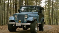 an old blue jeep is parked in the woods