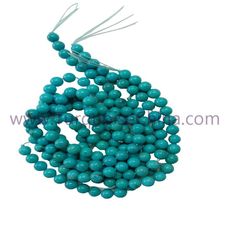 turquoise beads are arranged in a spiral pattern on a white background, with the string attached to