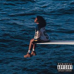 a woman sitting on the edge of a boat in the ocean looking up at the sky