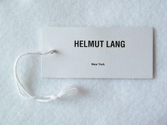 a piece of white paper with the words helmut lang on it and a string attached to it