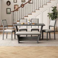 a dining room table with four chairs and a bench in front of the stair case