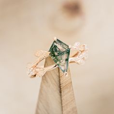 a green ring with leaves on it sitting on top of a piece of wood in front of a beige background