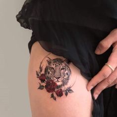 a woman's thigh with a tiger and roses tattoo on the lower half of her leg