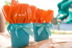 orange plastic forks are in blue cups with bows