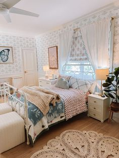 a bed room with a neatly made bed next to a window and a rug on the floor