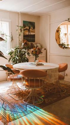 a dining room table surrounded by chairs in front of a potted plant on a rug