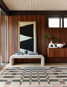 a living room with wood paneling and white vases on the table next to it