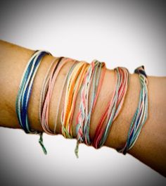 a woman's arm with several different colored bracelets on top of each other