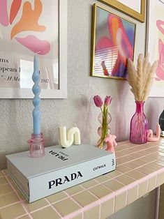 a table topped with books and vases filled with flowers next to pictures on the wall