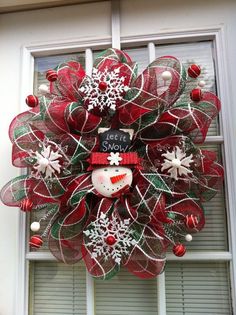 a red and green mesh wreath with snowflakes on the front window sill