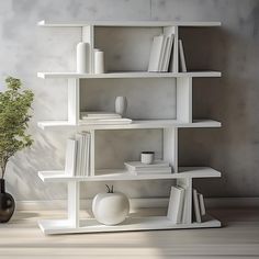 a white shelf filled with books and vases on top of a hard wood floor