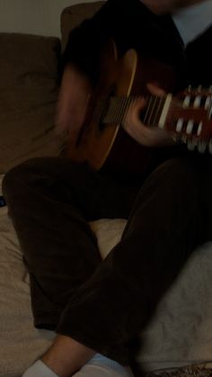 a man sitting on top of a bed playing a guitar