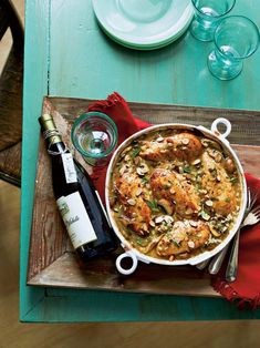 a bowl of food and some wine on a wooden tray with red napkins next to it