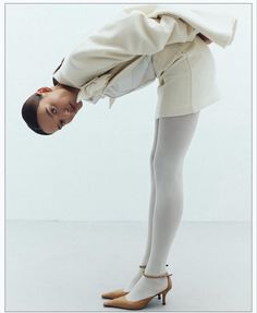 a woman in white tights and high heels posing for the camera with her hands on her head