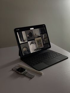 an open laptop computer sitting on top of a table next to a cell phone and pen