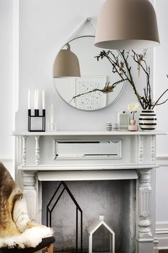 a dog is sitting in front of a fireplace with a mirror on the wall above it