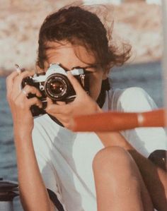 a person sitting on the ground with a camera in front of their face, taking pictures