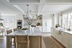 a large kitchen with white cabinets and marble counter tops, along with an island in the middle