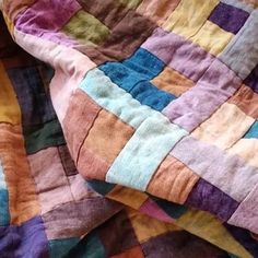 a colorful quilt is laying on top of a bed sheet with an orange, blue, yellow and pink checkerboard pattern