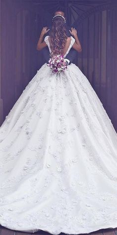 a woman in a white wedding dress is looking at the back of her gown,